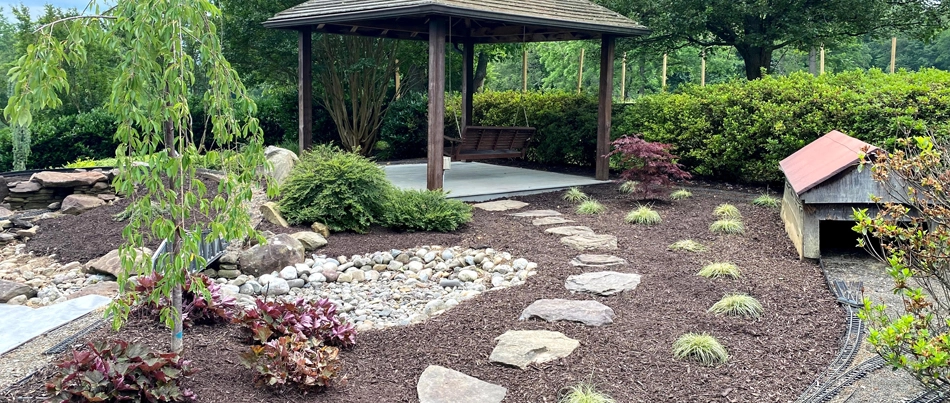 A landscape area in Bristow, VA, with plants, mulch, and a water feature.